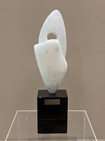 Front view of white abstract alabaster sculpture on black stone base