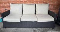 Front view of three-seater resin wicker sofa with all cushions in place