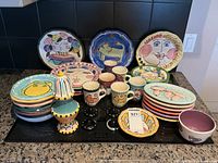 Wide view of the entire dish set showing plates, mugs, shakers, and a small bowl arranged on a counter.