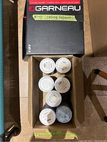 Photo top view of new boxed Garneau cycling helmet and seven decorative tissue dispensers in a box.