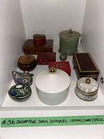 Front view of 11 small decorative containers showing variety of materials and shapes