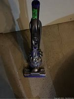 Full upright view of Dyson vacuum cleaner showing handle, cyclone bin, and cleaning head.