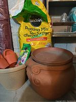 Photo showing open bag of Miracle-Gro Potting Mix soil, large terracotta pot, and beige plastic pot