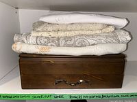 Stack of vintage lace linens on top of a wooden flatware box
