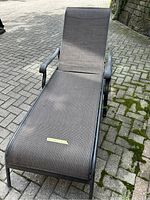 Metal mesh outdoor lounge chair on paved surface. Shows full side view with wheels visible and armrests.