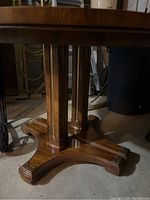Pedestal base of round table showing four curved feet and wood finish