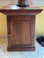 Front view of the small wooden side table showing cupboard door and knob, wood grain, and top surface.