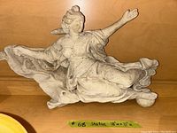 Full view of the stone or concrete statue seated woman with outstretched arm on a wooden surface with size label