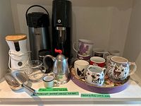 Photo of Sodastream machine, coffee grinder, stovetop espresso maker, assorted mugs, scoops, and glass coffee pot