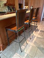 Three wood and metal barstools positioned at a kitchen counter, showing their full profile and size.