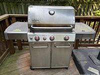 Front view of closed grill lid with Weber logo, side shelves and control knobs visible