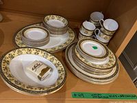 Overall grouping of plates, bowls, mugs and serving pieces on shelf