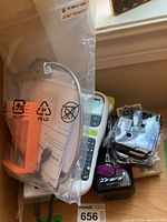 Brother P-Touch label maker behind sealed plastic bag with accessories and manuals.