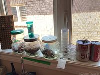 Coins mounted on wooden board and variety of coin jars and banks on windowsill