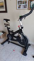 Full side view of the Frequency Fitness S20 stationary bike showing black frame, seat with backrest, pedals, and handlebars.
