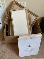 Box of assorted picture frames including decorative gold and plain wood frames, some empty, some with backing.