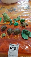 Full lot of frog figurines displayed on a table including ceramic and metal pieces
