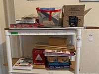 Full view of shelving with assorted boxed games, a plastic bin, wooden boxes, and puzzles.