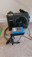 Photo of GE Power Sound 8 track player, microphone, clip light, and blue 8 track tapes on carpeted floor.