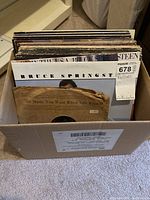 MaxSold lot tag on record box and visible album covers of Bruce Springsteen and others