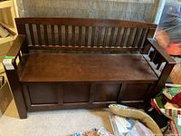 Bench shown from front view highlighting slatted backrest and solid armrests with panel detailing on front storage compartment.