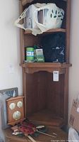 Wooden corner wall shelf with barometer and thermometers on lower shelf, small insect figurines on base shelf, medical masks and gloves in plastic bags on upper shelves; some cardboard boxes to side