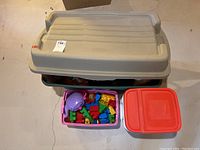 Closed plastic storage bin with lid, pink container with colorful Duplo blocks, and red container with lid.
