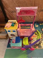 Lot consists of three main items: Fisher-Price toy washer, pink doll dresser with hangers, and purple-green doll stroller.