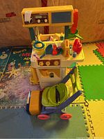 View of Fisher-Price kitchen playset and doll stroller showing overall condition and set arrangement
