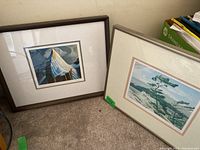 Two framed wall art prints leaning against the wall on the floor, showing both artworks and framing style.