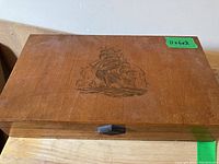 Top of wooden box showing engraved sailing ship design.
