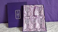 Original purple box containing five small crystal stemmed glasses with faceted cut bowls. One glass is missing from the six-slot box.