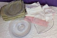 Photo showing three glass trays: one heart-shaped with small bowl, one round tray, and one rectangular tray with pattern. Background includes folded textiles.