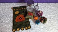 Harvest decor set on white background including felt banners and pillows, large Ball mason jar with metal lid, glass decanter with moon-shaped stopper, and ceramic pumpkins in orange, blue, and purple colors.