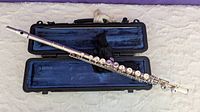 Silver-plated Selmer flute assembled and placed inside a hard black case lined with blue velvet.