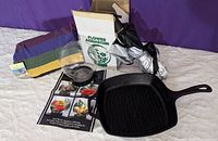Photo showing all items including folded multi-colored hammock, glass Flower Aquarium with original box, black cast iron Lodge grill pan, and folded car window umbrella sunshade.