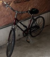 Full view of a vintage two-wheel bicycle positioned indoors showing frame, wheels, saddle and handlebars.