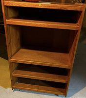 Front view of teak wood bookcase with three shelves and one bottom shelf section, showing the open shelving compartments.