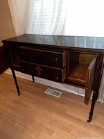 Mahogany buffet sideboard against wall with window and white curtains. Doors and drawers open showing interior storage space.