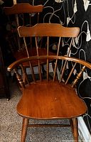 Wooden side chair showing front and partial side view, highlighting curved backrest, multiple spindles, and armrests