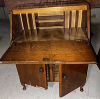 Wooden desk drawer with hinged lid open showing compartments inside and two front doors open