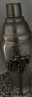 Silver-tone martini shaker showing 'Vienna' emblem and grape decoration on front, displayed upright