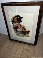 Framed Norman Rockwell print showing elderly man fishing with umbrella, angled view of whole piece including frame and matting
