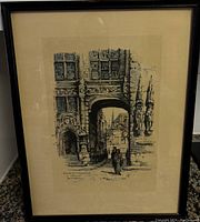 Framed black and white architectural print showing detailed archway and figures.