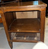 Front view of wooden bedside table showing two open shelves and surface wear