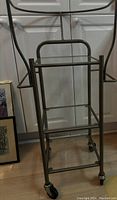Metal bar cart with glass shelves and four wheels