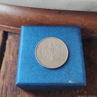 Photo of the coin placed on a blue square box showing the eagle and text 'BUNDESREPUBLIK DEUTSCHLAND'.