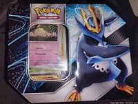 Photo of the Pokémon Empoleon metal tin from above, with a portion of the cards visible through a plastic window.