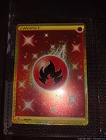 Single collectible Pokémon Fire Energy card with gold holographic background and star sparkle effects, center flame energy symbol, yellow border.