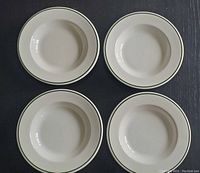 Top view showing all four identical soup bowls arranged symmetrically on a dark surface, highlighting their round shape and green rim detail